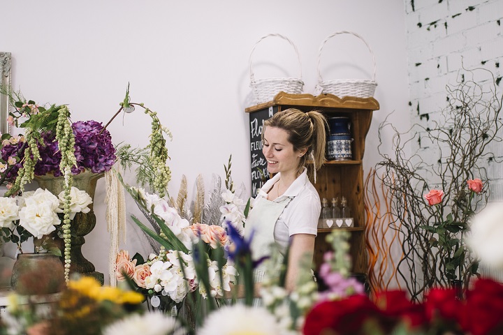 Fleuriste dans sa boutique quivprepare ses commandes et encaisse avec un logiciel de caisse ses clients